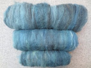 Three drum carded rolls of shetland sheep fleece in mid tones of grey and blueish green