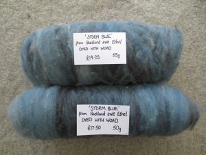 Carded batts of fleece in blue and grey rolled up and labelled storm blue