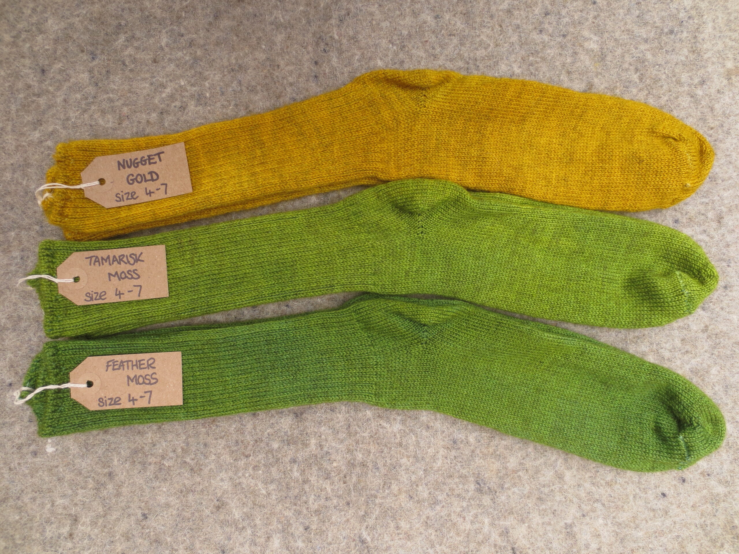 3 pairs of socks labelled Nugget Gold, Tamarisk Moss and Feather Moss